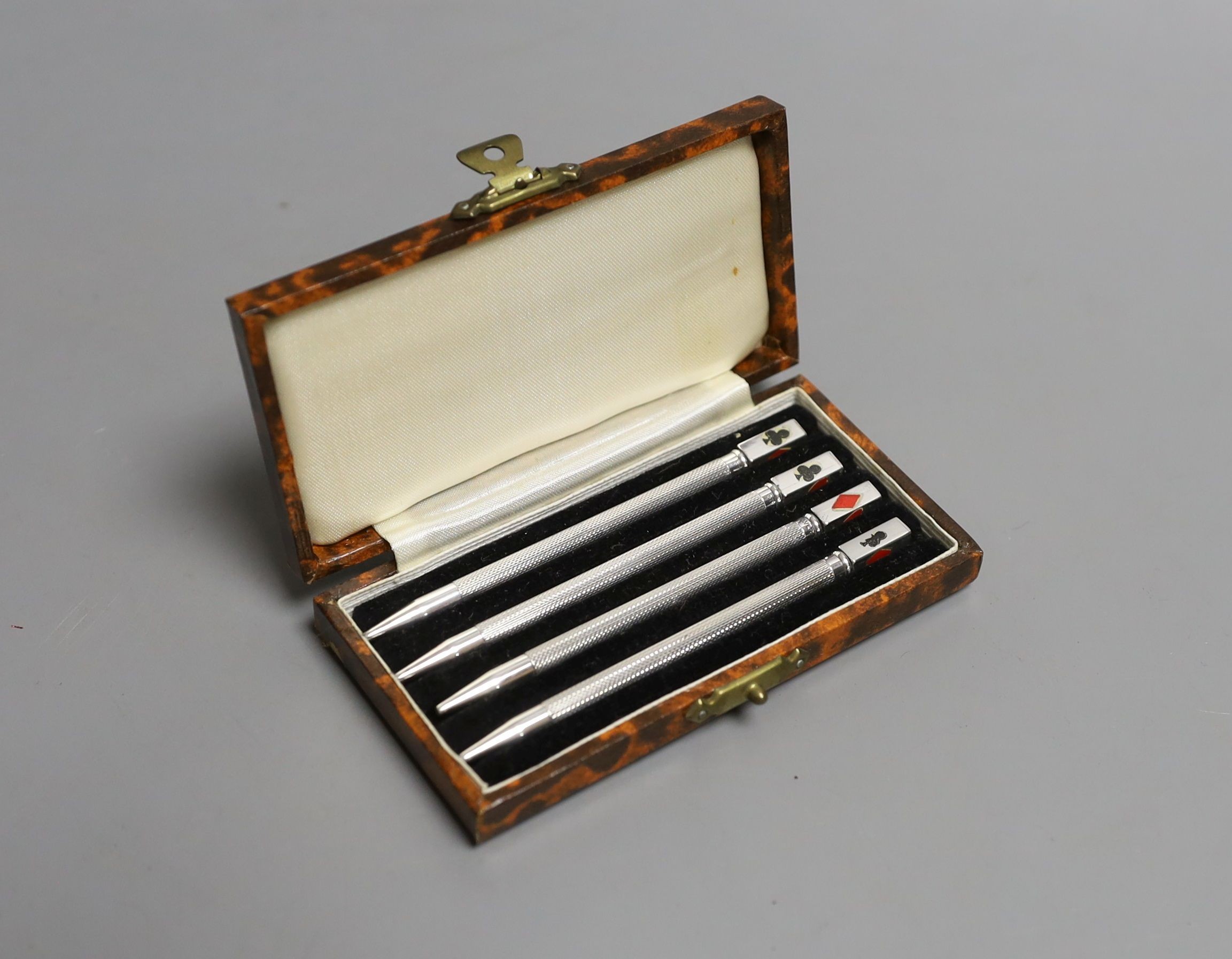 A cased set of four engine turned sterling and enamel bridge pencils, 9cm.